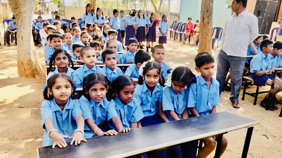 Schulkinder in Karnataka an einer Schulbank aus recyceltem Abfall